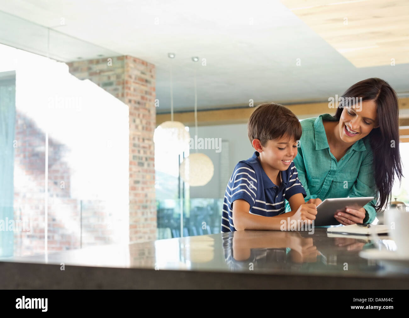 Mother and son using tablet computer in kitchen Stock Photo