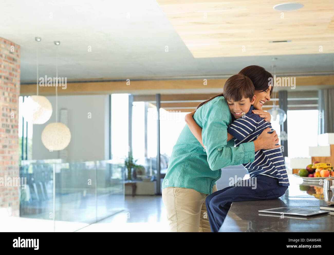 Mother hugging son in kitchen Stock Photo