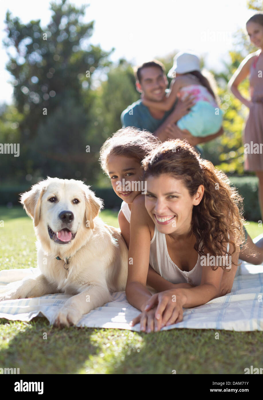 Mother, daughter and dog laying in grass Stock Photo