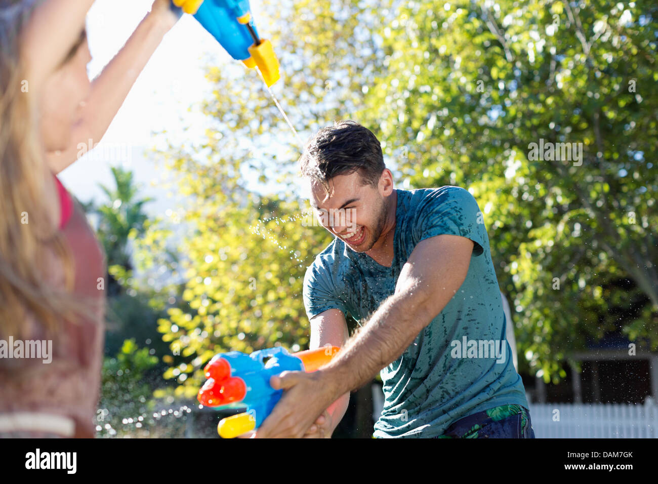 Couple playing with water guns in backyard Stock Photo