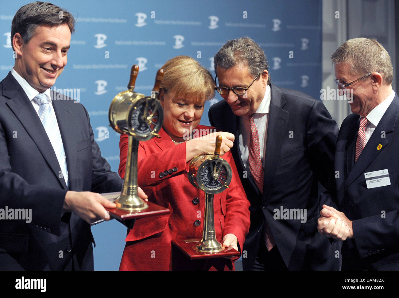 Federal Chancellor Angela Merkel and Lower Saxony's Minister President David McCallister (L-R) recieve engine order telegraphs from Wilhelmshaven's Mayor Eberhard Menzel, while the Parliamentary Secretary at the Federal Ministry of Economics and Government Coordinator for Maritime Economy, Hans-Joachim Otto (R), looks on, at the 7th National Maritime Conference in Wilhelmshaven, Ge Stock Photo