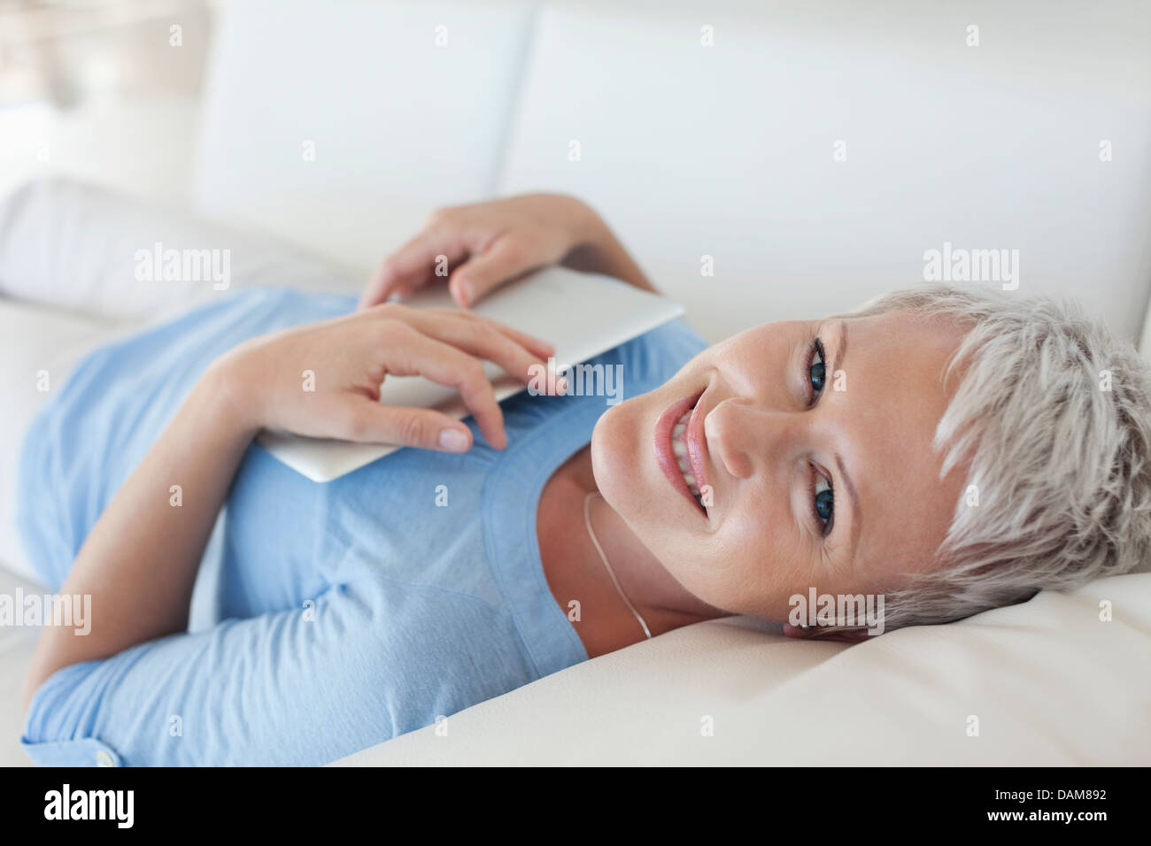 Woman holding tablet computer on sofa Stock Photo