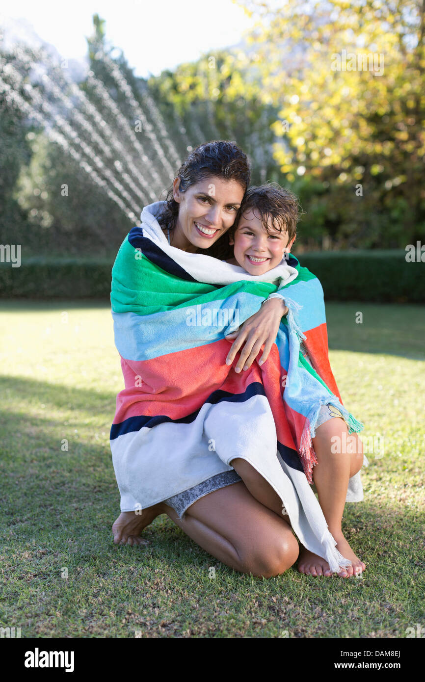 Mother and son wrapped in towel in backyard Stock Photo