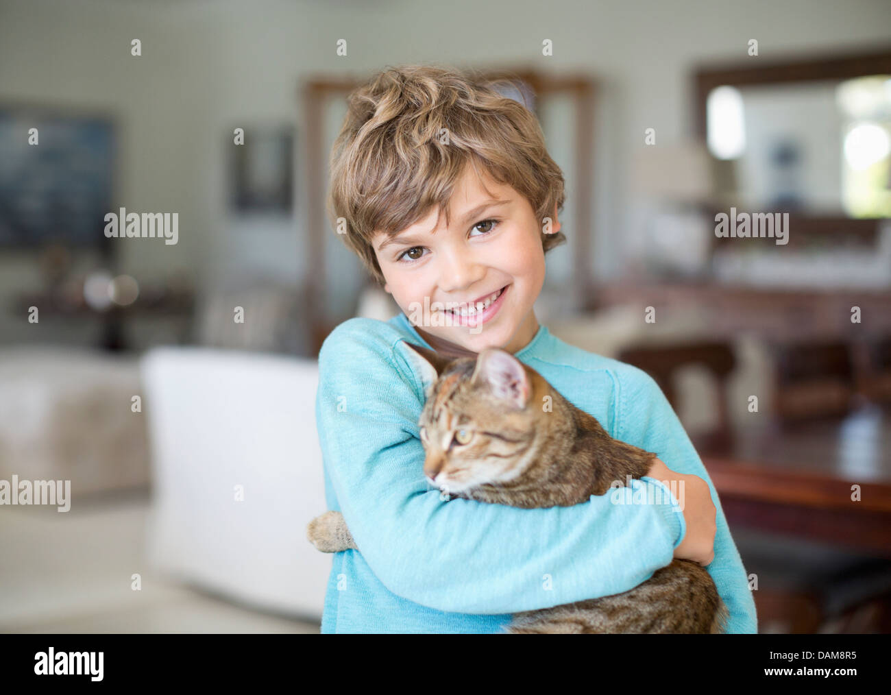 Boy hugging cat in living room Stock Photo