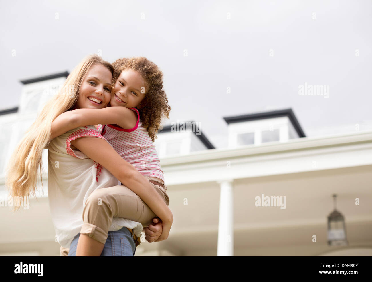 Mother and daughter hugging outside house Stock Photo