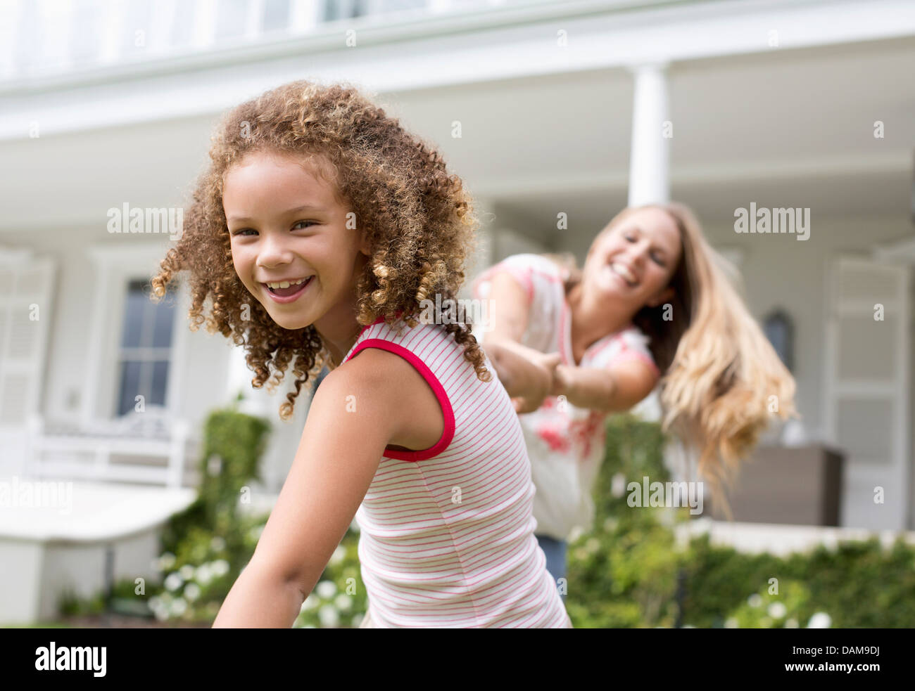 Mother and daughter playing outside house Stock Photo