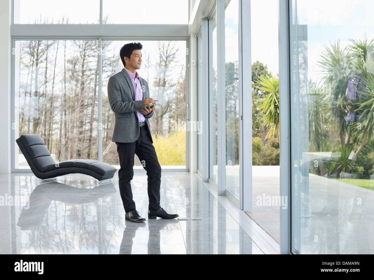 Businessman standing at office window Stock Photo