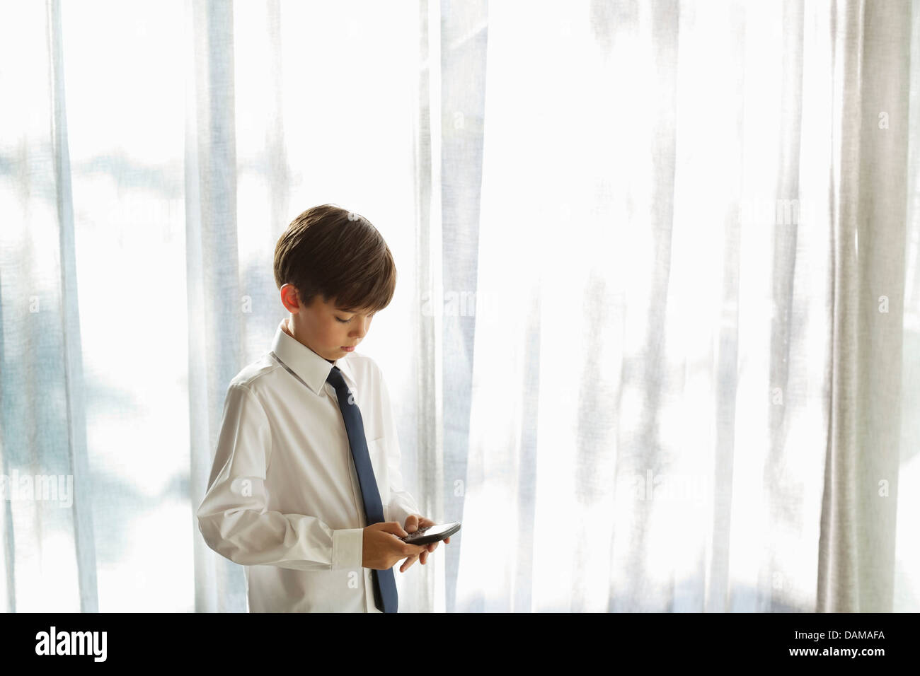 Boy in shirt and tie using cell phone Stock Photo