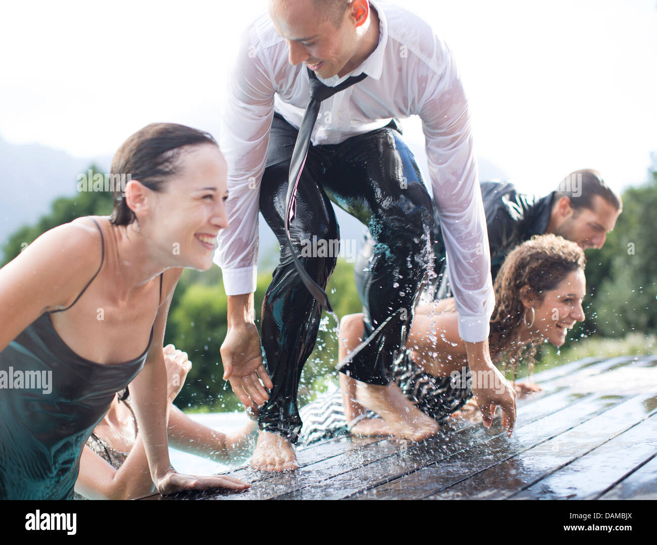 Fully dressed friends climbing out of swimming pool Stock Photo