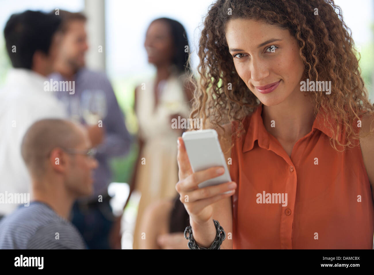 Woman using cell phone at party Stock Photo