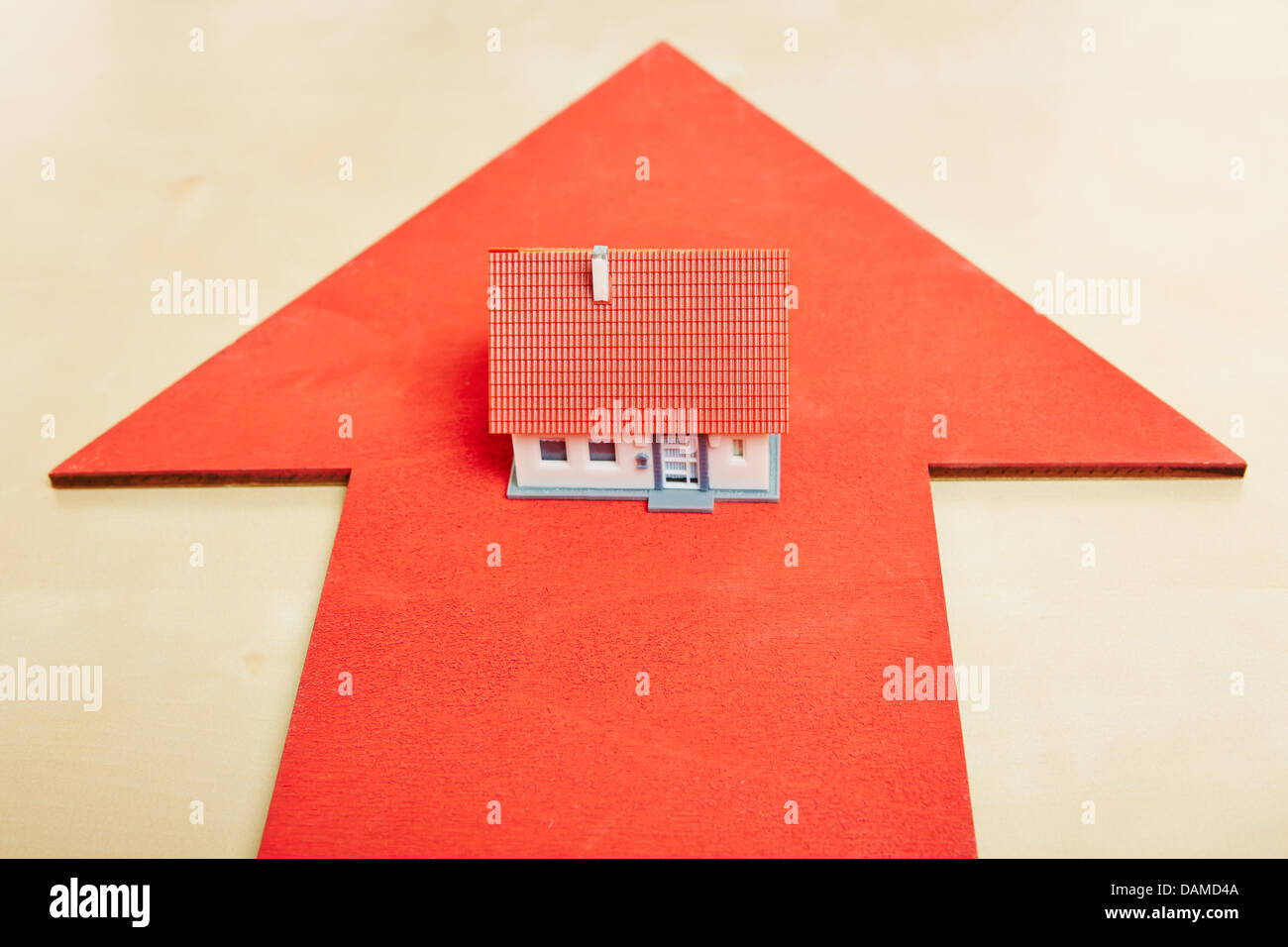 Little house standing on a big red arrow Stock Photo