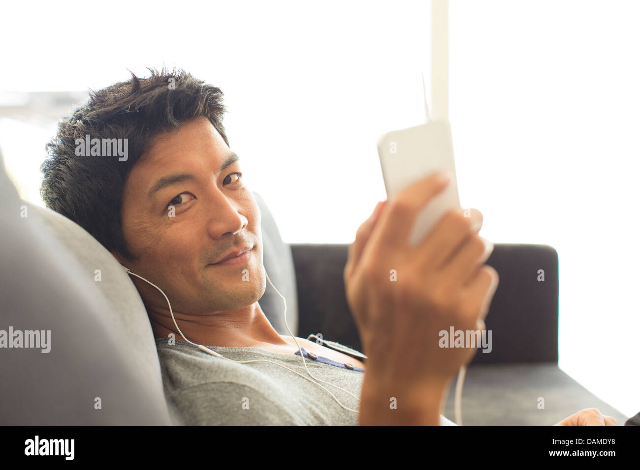 Man listening to headphones on sofa Stock Photo
