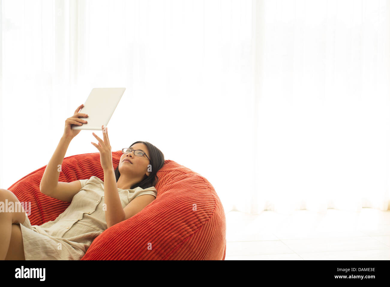 Woman using tablet computer in beanbag chair Stock Photo