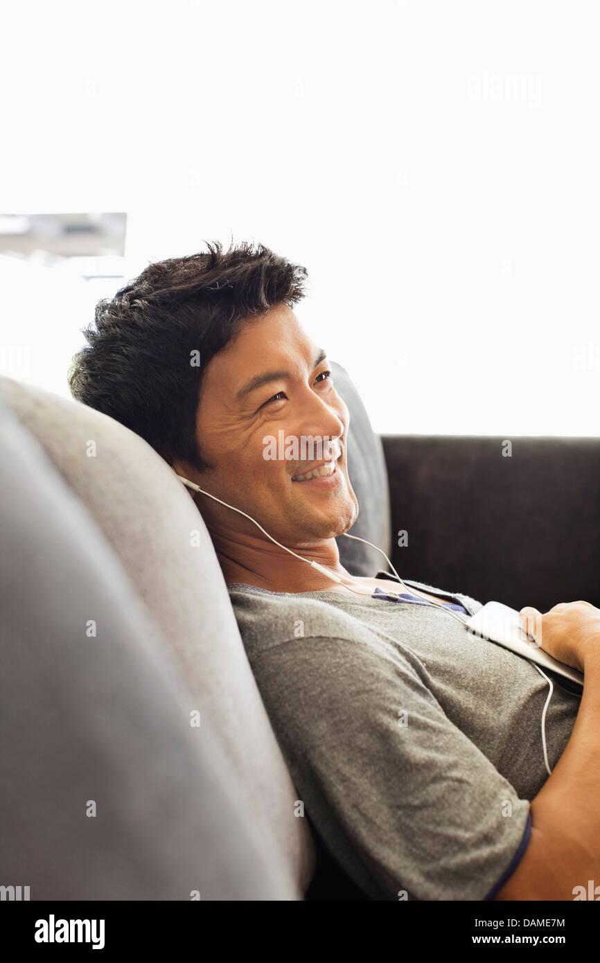 Man listening to headphones on sofa Stock Photo