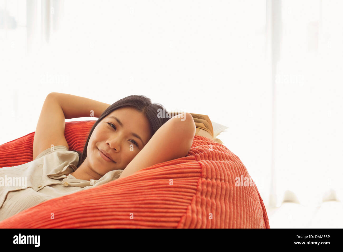 Smiling woman relaxing in beanbag chair Stock Photo