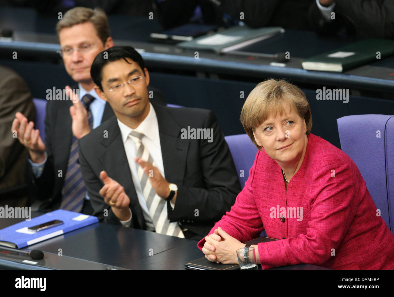 Chancellor Angela Merkel recieves applause from Economy Minister Philipp Roesler (C) and Foreign Minister Guido Westerwelle (L) at the Bundestag in Berlin, Germany, 09 June 2011. Earlier, Chancellor Merkel made a governmental statement on energy politics. Photo: Doreen Fiedler Stock Photo