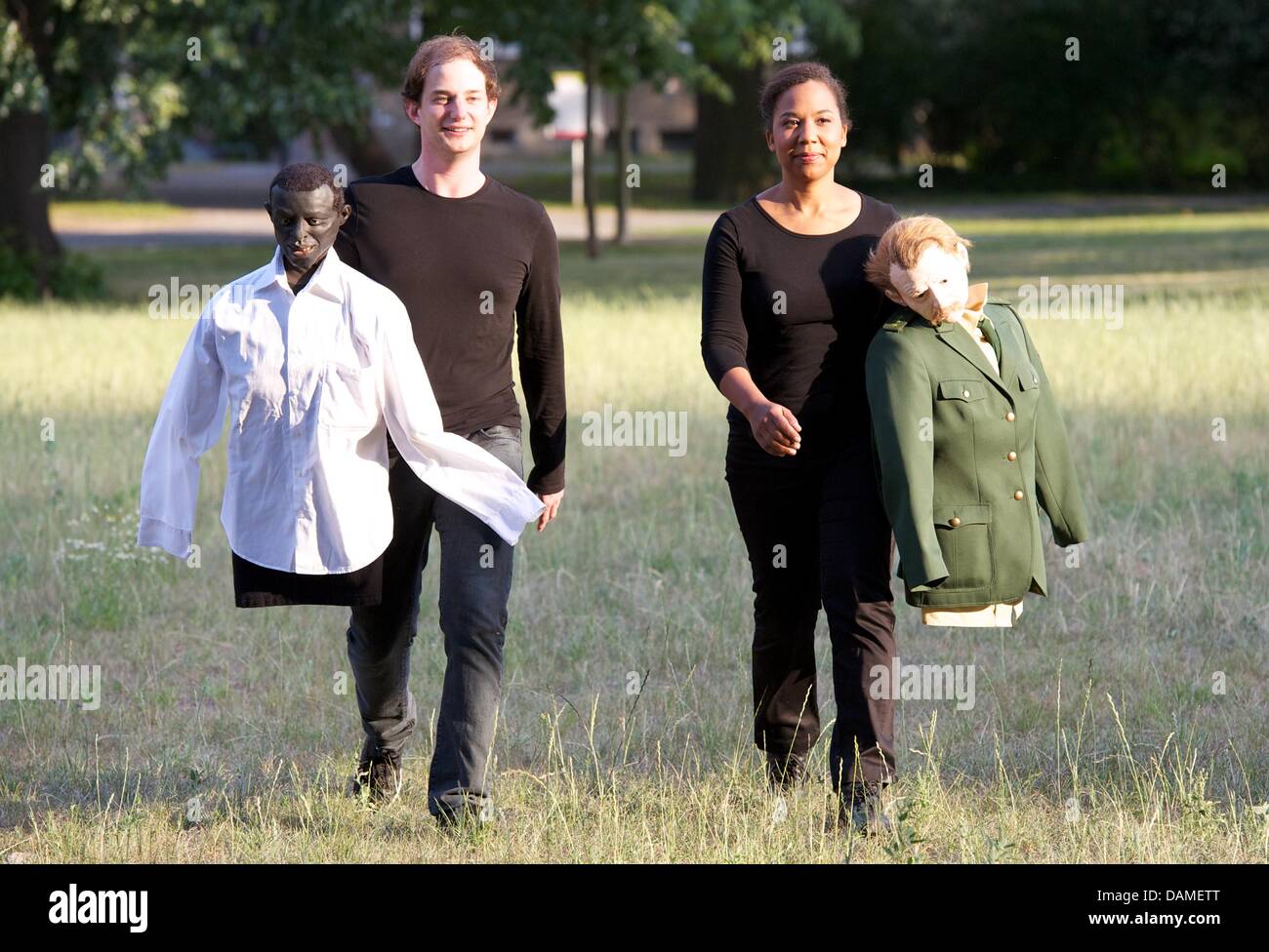 Actors Jan Kersjes (L) and Abak Safaei-Rad from Anhaltinische Theater Dessau carry dolls representing Oury Jalloh (L) and a police officer in the Stadtpark in Dessau, Germany, 09 June 2011. The theatre is thematisizing the tragic death by fire of asylum seeker Oury Jalloh in a police cell with a play directed by Nina Guehlstorff and Dorothea Schroeder. There will be four performanc Stock Photo