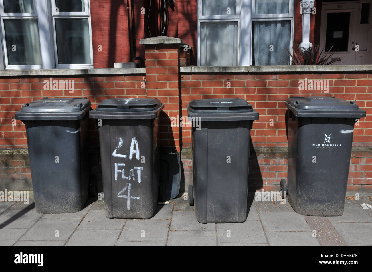 Four black rubbish bins, lined up on street, London Stock Photo Alamy