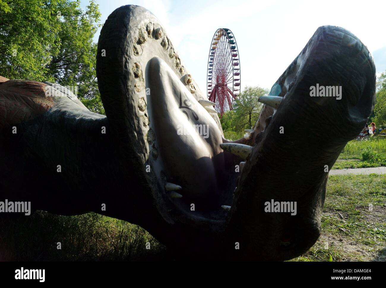 A life-sized dinosaur model lies on the ground in front of a ferris wheel in the Plaenterwald amusement park in Berlin, Germany, 26 May 2011. The Plaenterwald was the largest amusement park in East Germany but was closed down 10 years after the German Reunification. The park has been reopened for only a brief period of time featuring numerous attractions for visitors. Photo: Mauriz Stock Photo