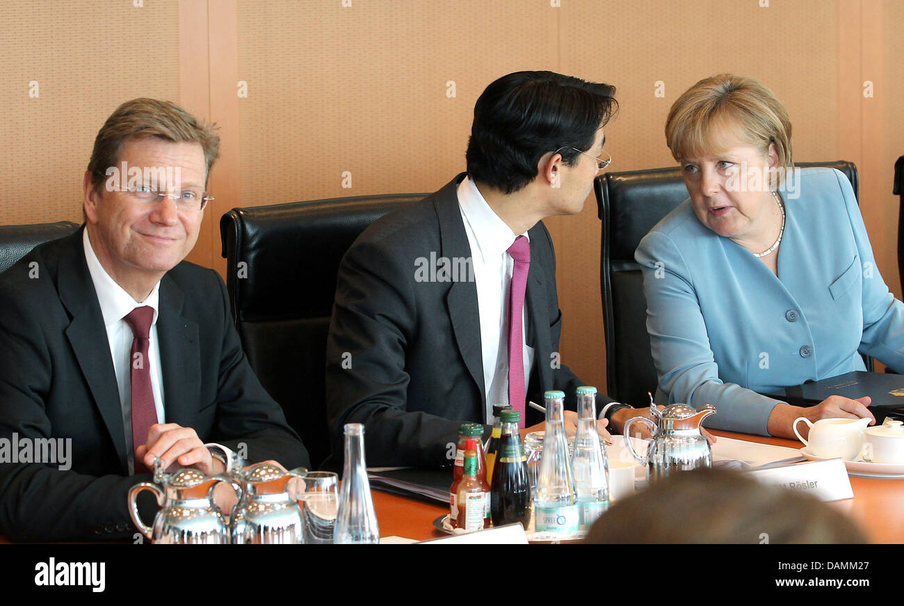 Chancellor Angela Merkel speaks to Federal Economy Minister and Vice Chancellor Philipp Roesler prior to the cabinet meeting inside the Chancellory in Berlin, Germany, 22 June 2011. On the left sits Federal ForeiGn minikster Guido Westerwelle. Photo: WOLFGANG KUMM Stock Photo