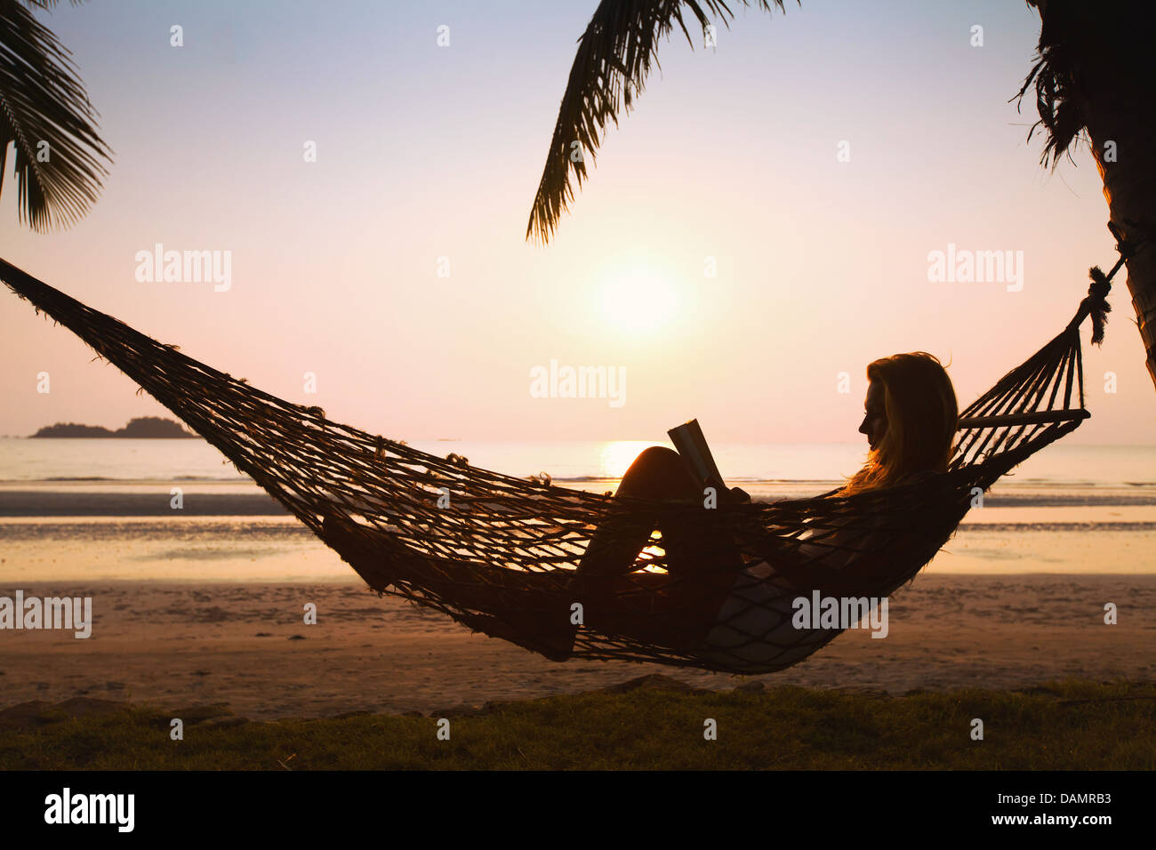 silhouette of woman relaxing in hammock on the beach Stock Photo