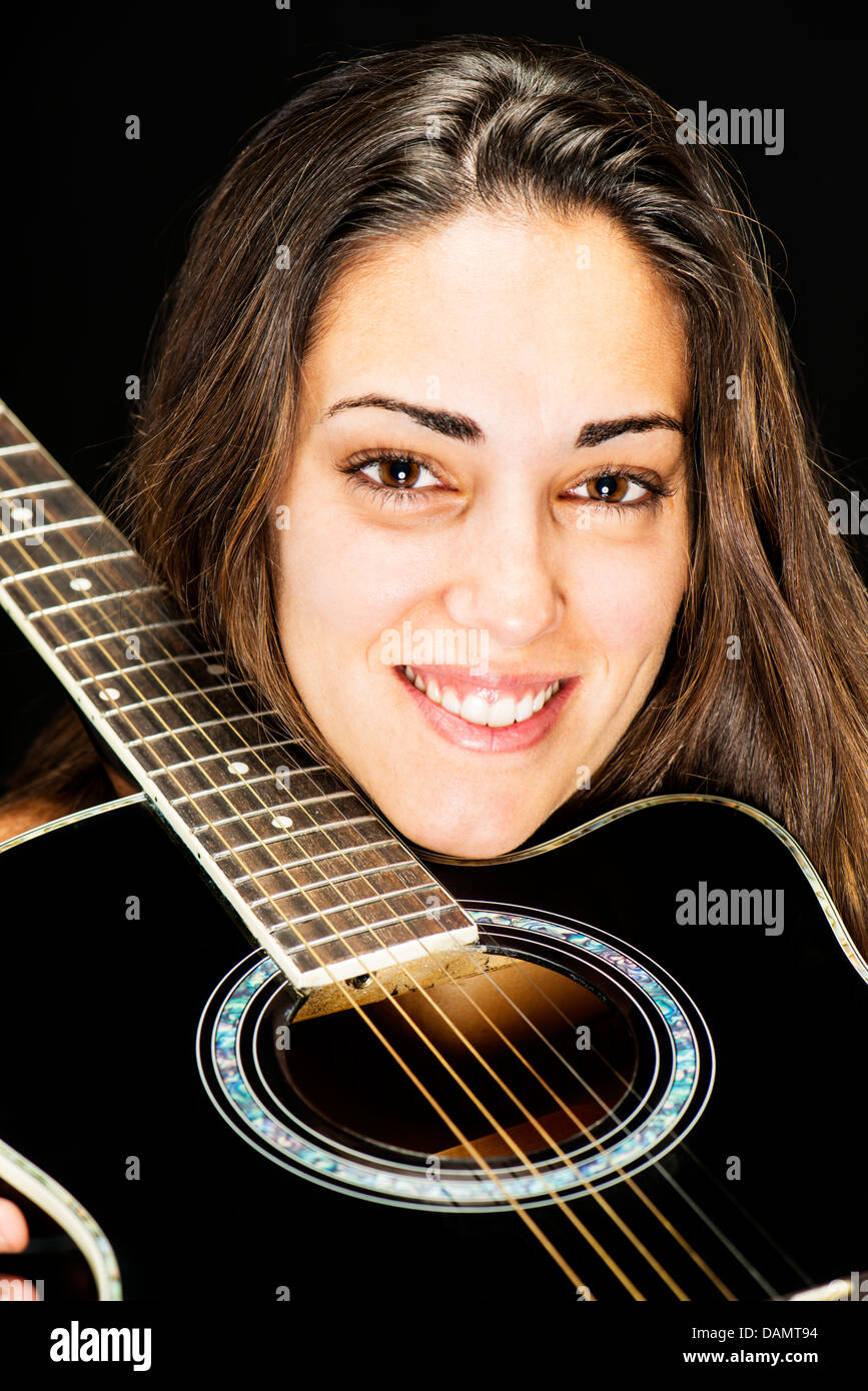 Studio portrait of a pretty young brunette woman holding an acoustic ...