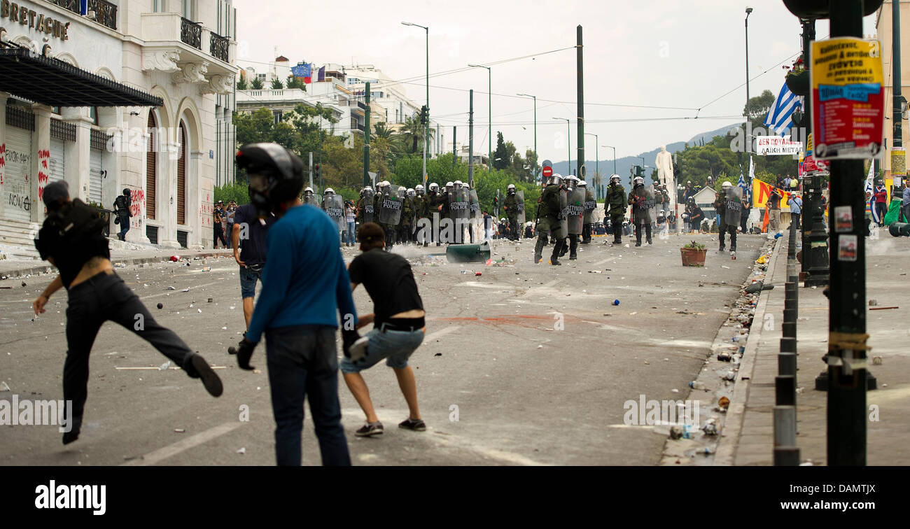 Demonstrators hurl stones at riot police during clashes in front of Greek Parliament on the second day of a 48-hour general strike in Athens, Greece, Wednesday, 29 June 2011. Millions of Greeks participated in the strike to oppose new heavy austerity measures which are part of a medium-term fiscal strategy framework 2012-2015 which is to be concluded in the parliament on Wednesday. Stock Photo
