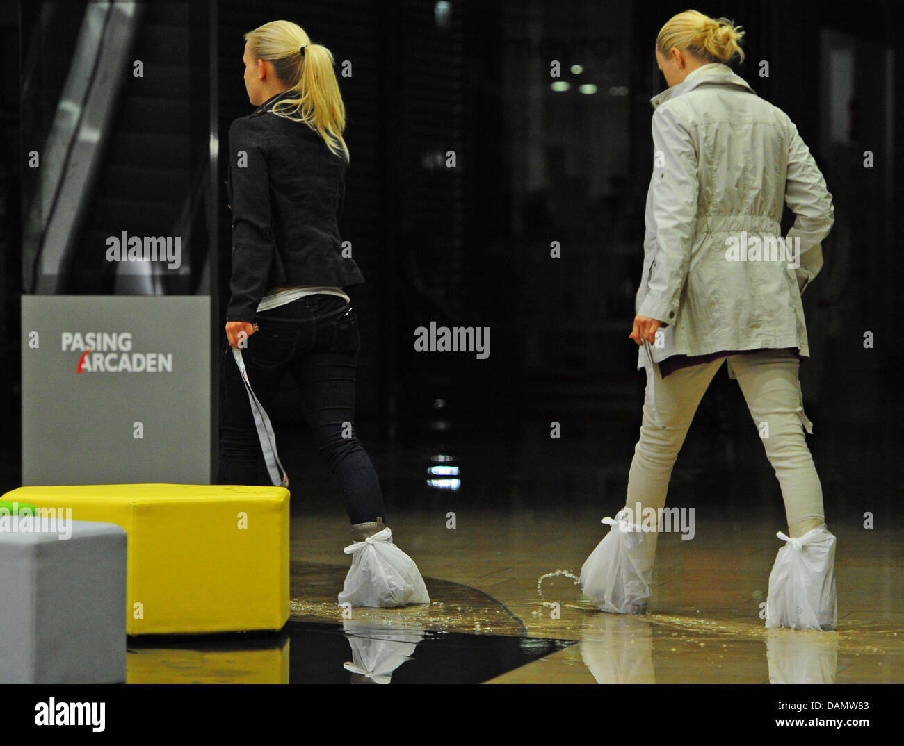 Women walk with plastic bags on the feet after heavy rains caused flooding in the downstairs of