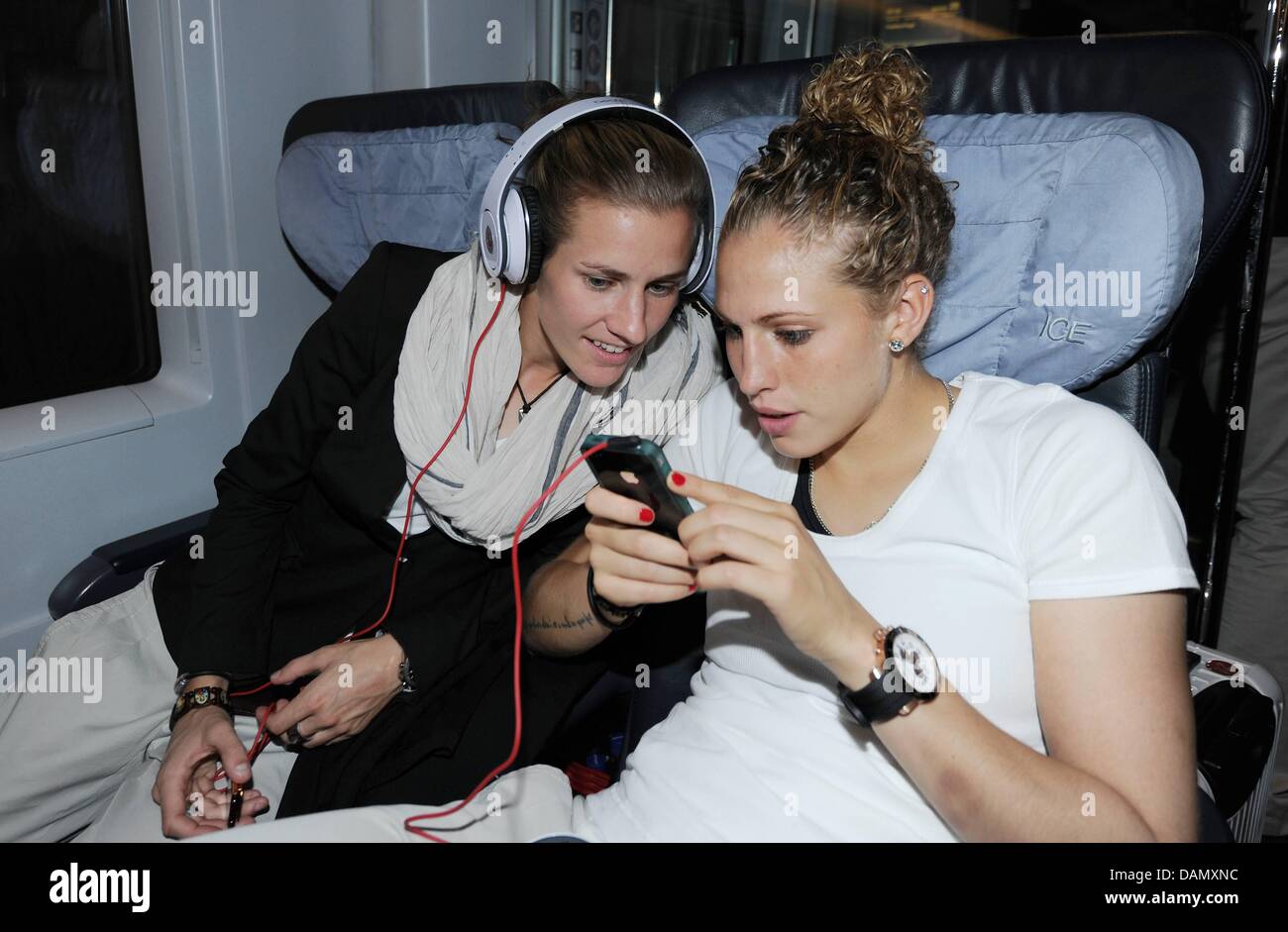 German women's national soccer players Simone Laudehr (L) and Kim Kulig listen to music during a ride in an ICE train from Frankfurt to Duesseldorf, Germany, 01 July 2011. Germany's next FIFA Women's World Cup match will take place in Moenchengladbach on 5 July 2011. Photo: Markus Gilliar/GES-Sportfoto/DFB Stock Photo