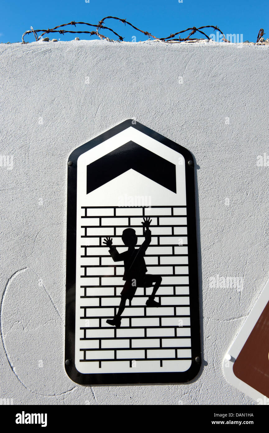 Sign Man Climbing up tall brick wall arrow up Stock Photo