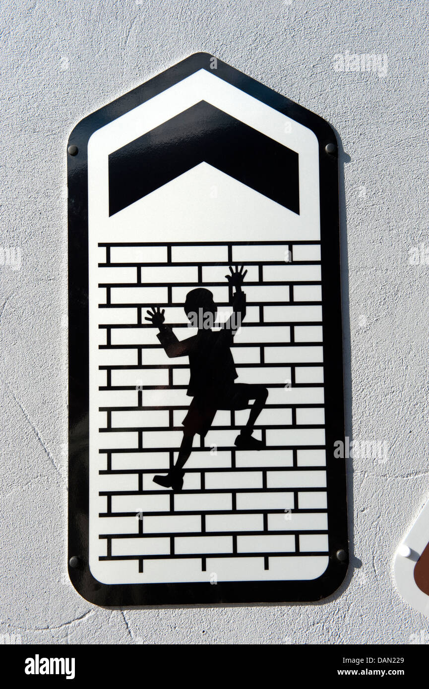 Sign Man Climbing up tall brick wall arrow up Stock Photo