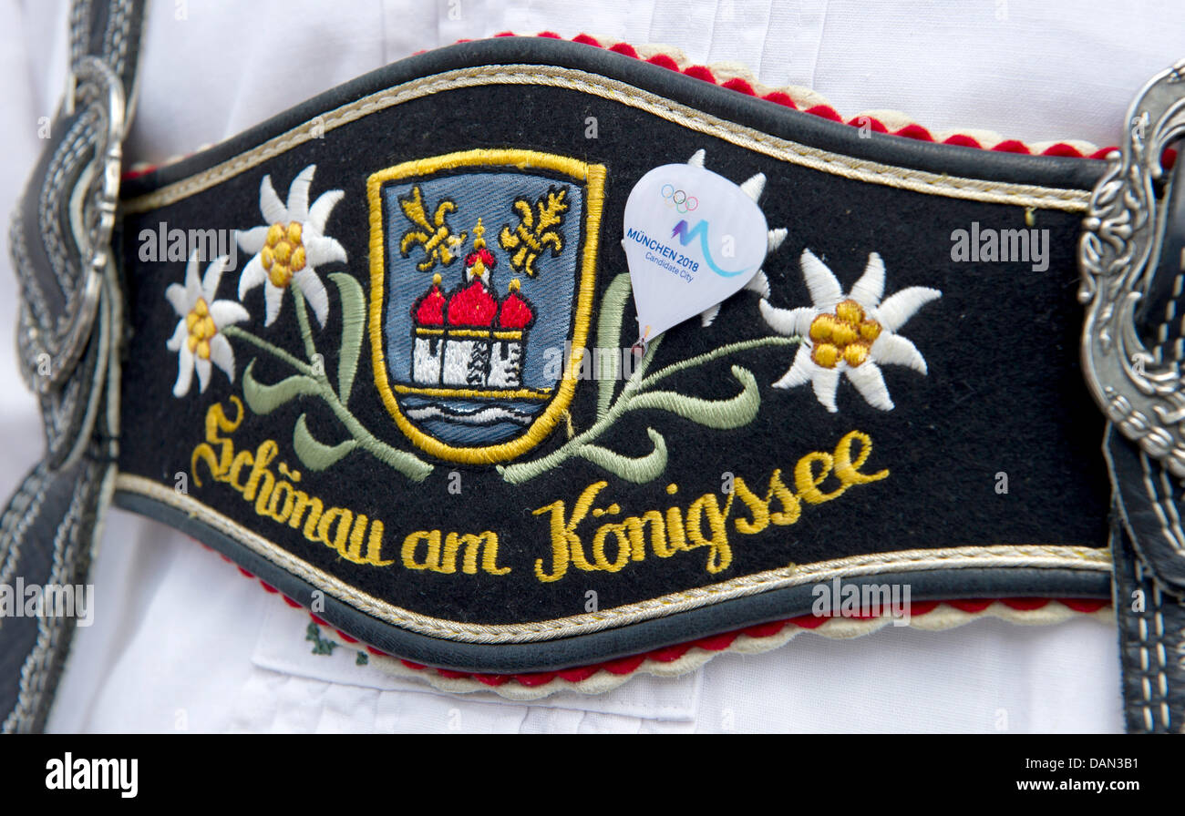 A man, wearing lederhosen embroidered with the coat of arms of the city  Schoenau am Koenigsee, wears a pin in the shape of a hot-air balloon and  reading 'Munich 2018 - Candidate