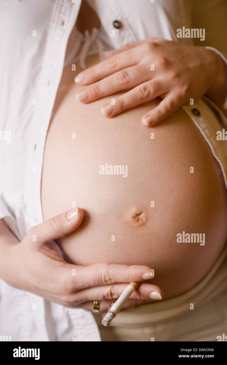 FILE) An archive photo dated 13 March 2008 shows the hands of a pregnangt  woman with a cigarette holding her belly in Neubrandenburg, Germany. Smoking  during pregnancy can lead to low birth