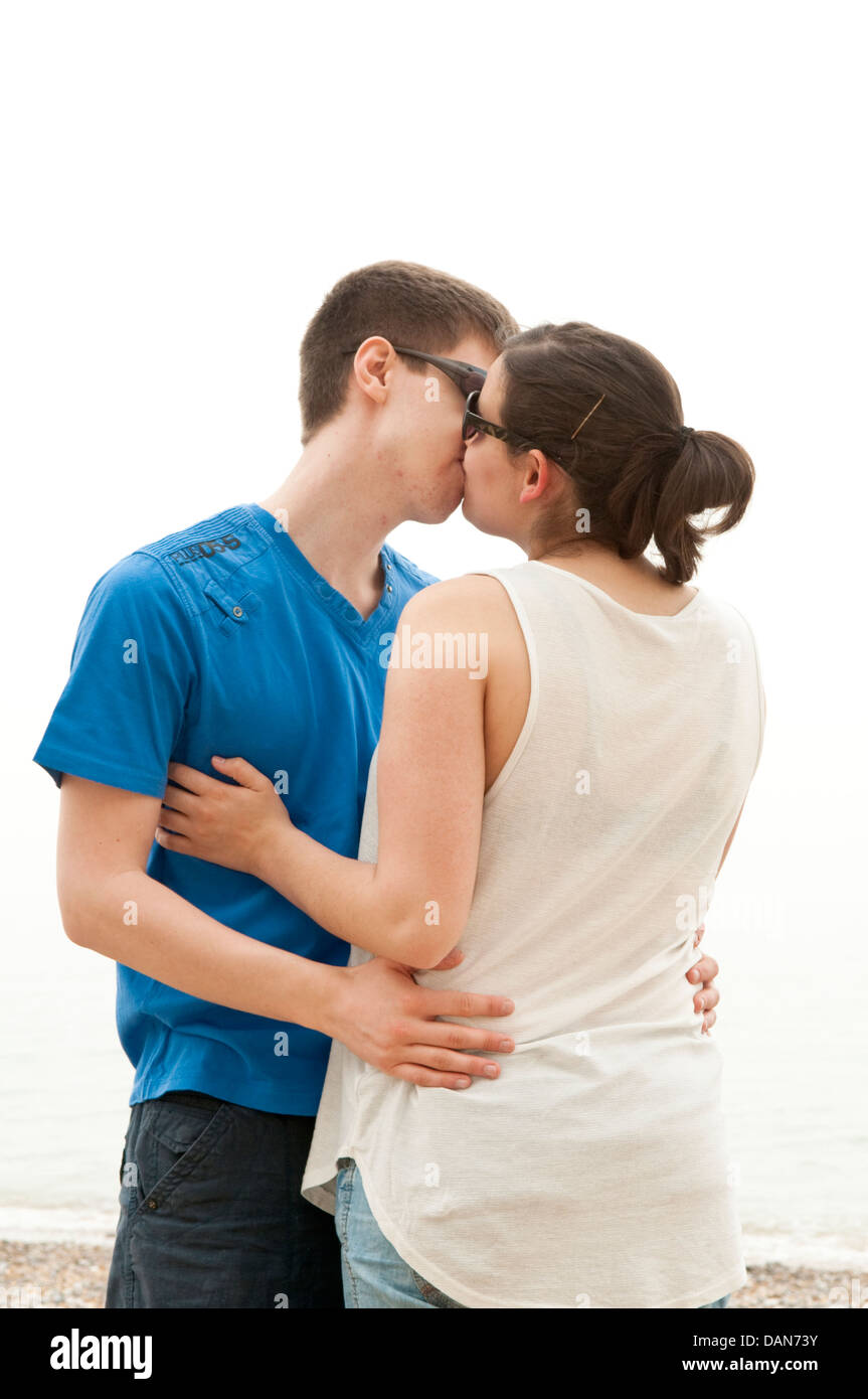 A young couple in their late teens or early twenties hugging and kissing on a beach Stock Photo