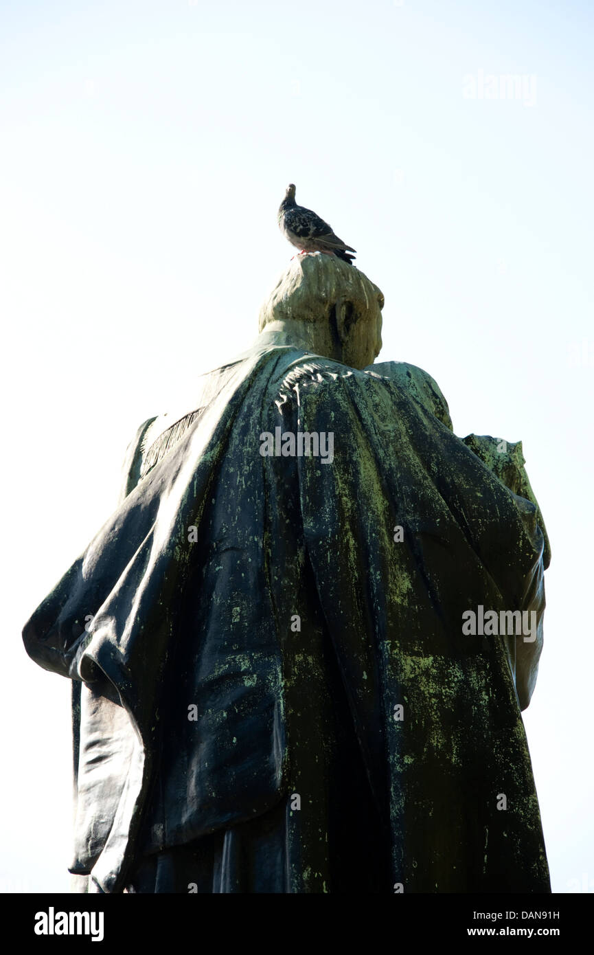 Pigeon Bird on head of bronze statue poo muck Stock Photo