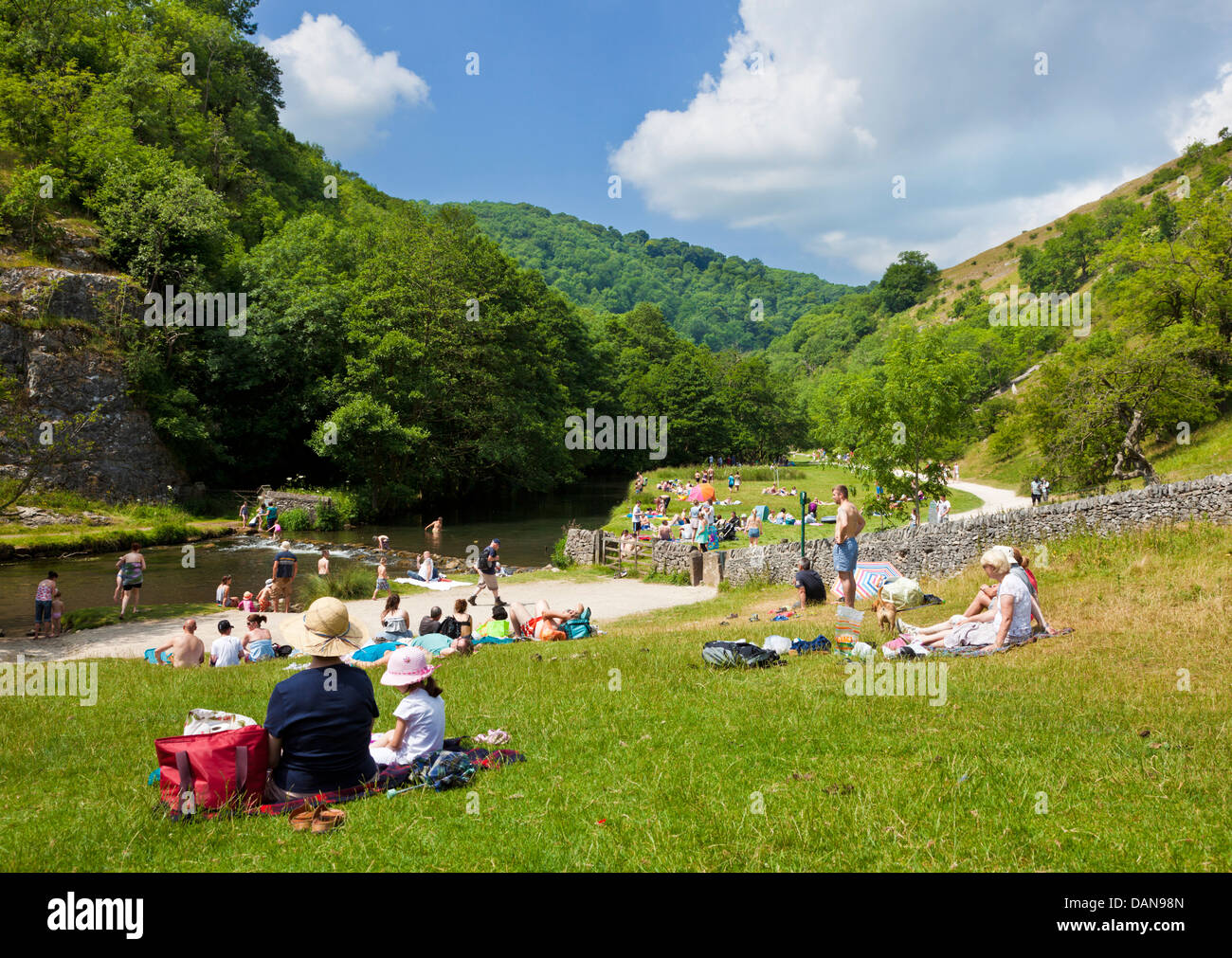 Tourists crossing River Dove on stepping stones in Dovedale Derbyshire peak district Stock Photo