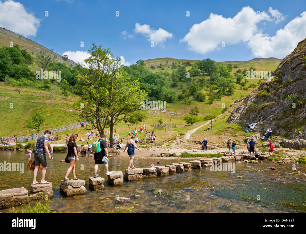 Tourists crossing River Dove on stepping stones in Dovedale Derbyshire peak district national park England UK GB EU Europe Stock Photo
