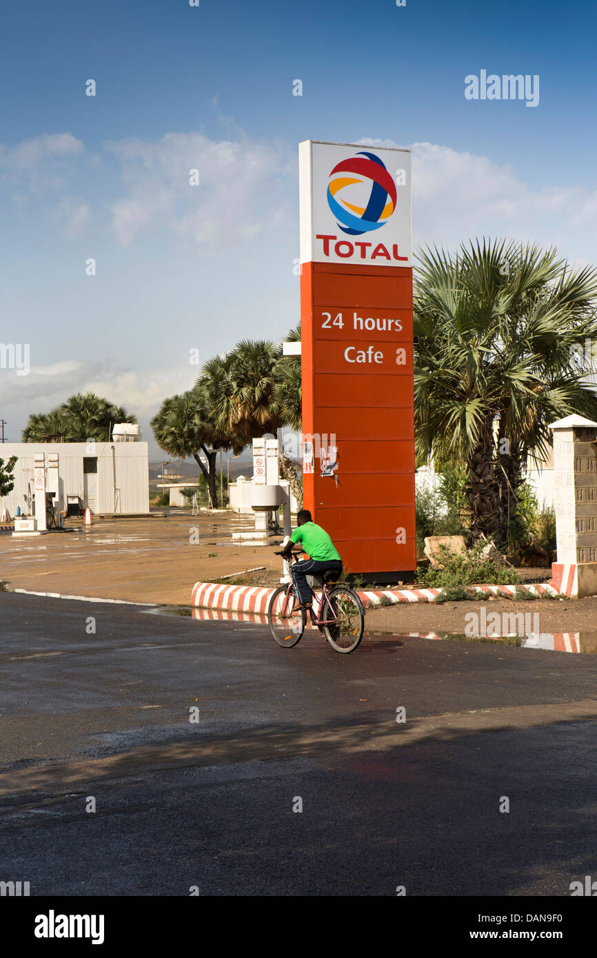 Africa, Eritrea, Massawa, Tualud Island, man cycling past Total Petrol station Stock Photo