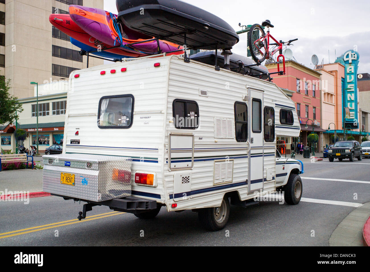 Camper truck with license plate that reads "Y Rent" carries kayaks