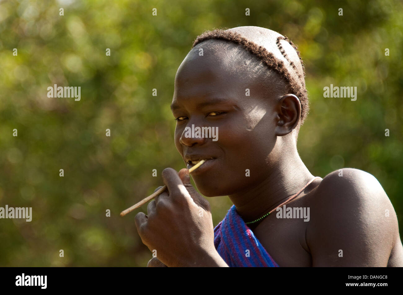 A Suri (Surma) shepherd with a stick in his mouth, Ethiopia Stock Photo