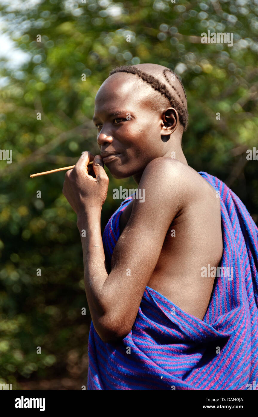 A Suri (Surma) young man with a stick in his mouth, Ethiopia Stock Photo