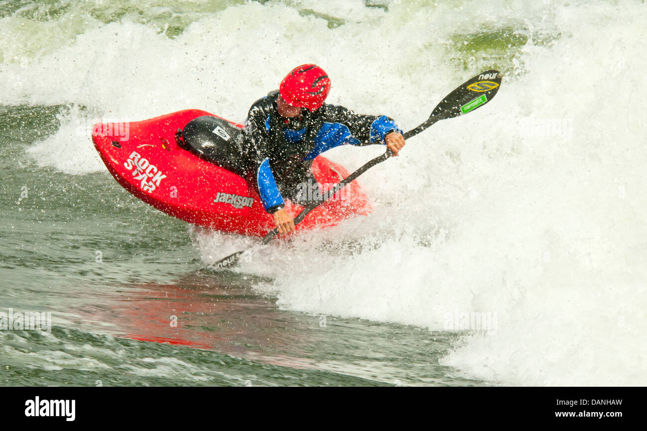 Freestyle kayaker kayaking through a powerful wave of rapids on the