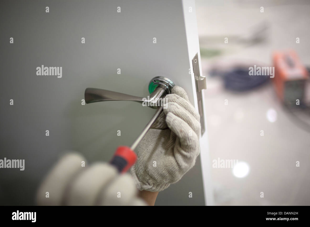 workers are installing a door lock with a screwdriver Stock Photo Alamy