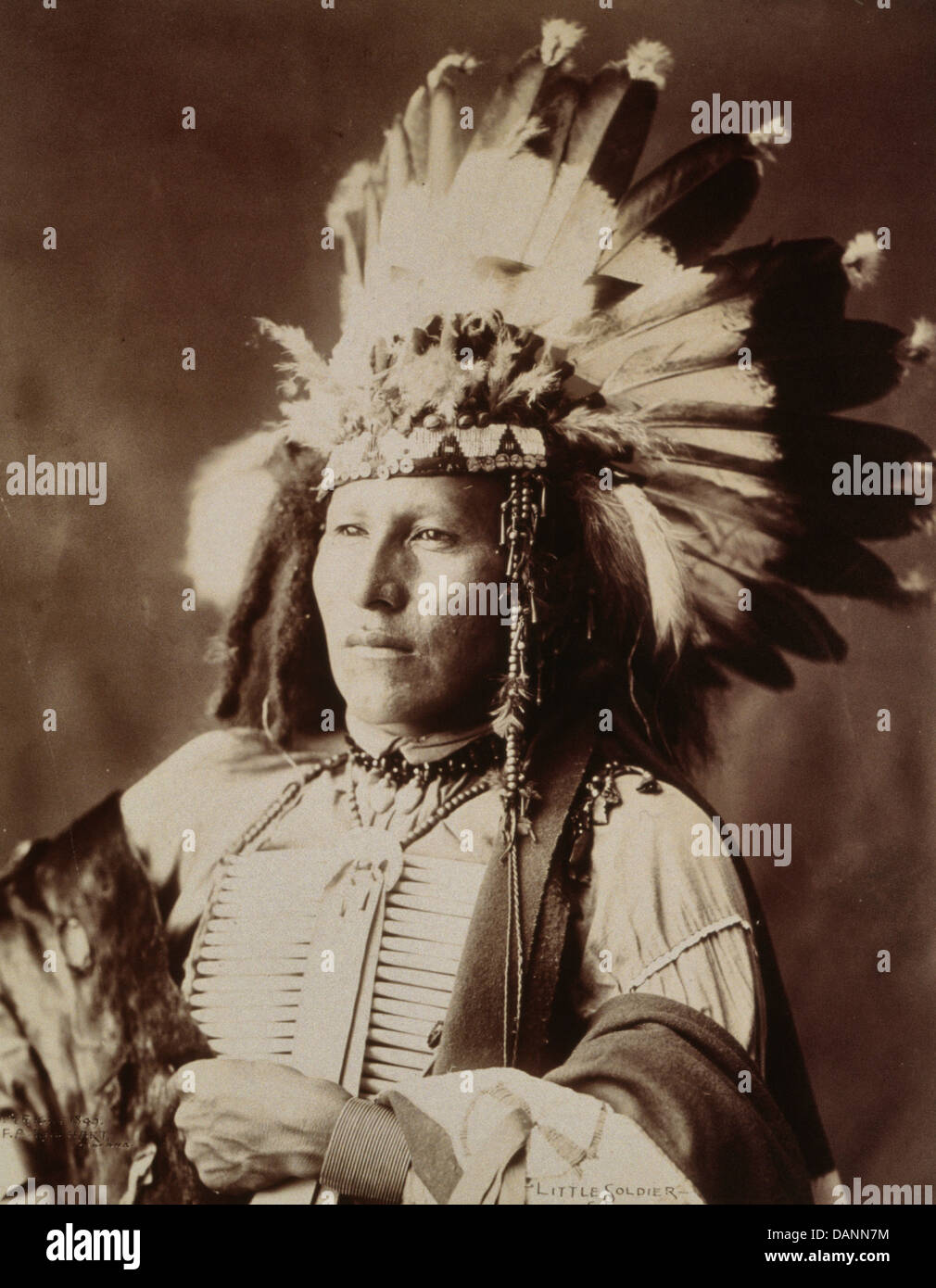 Little Soldier, half-length portrait, facing left, wearing breastplate and war bonnet, Sioux Warrior, circa 1899 Stock Photo