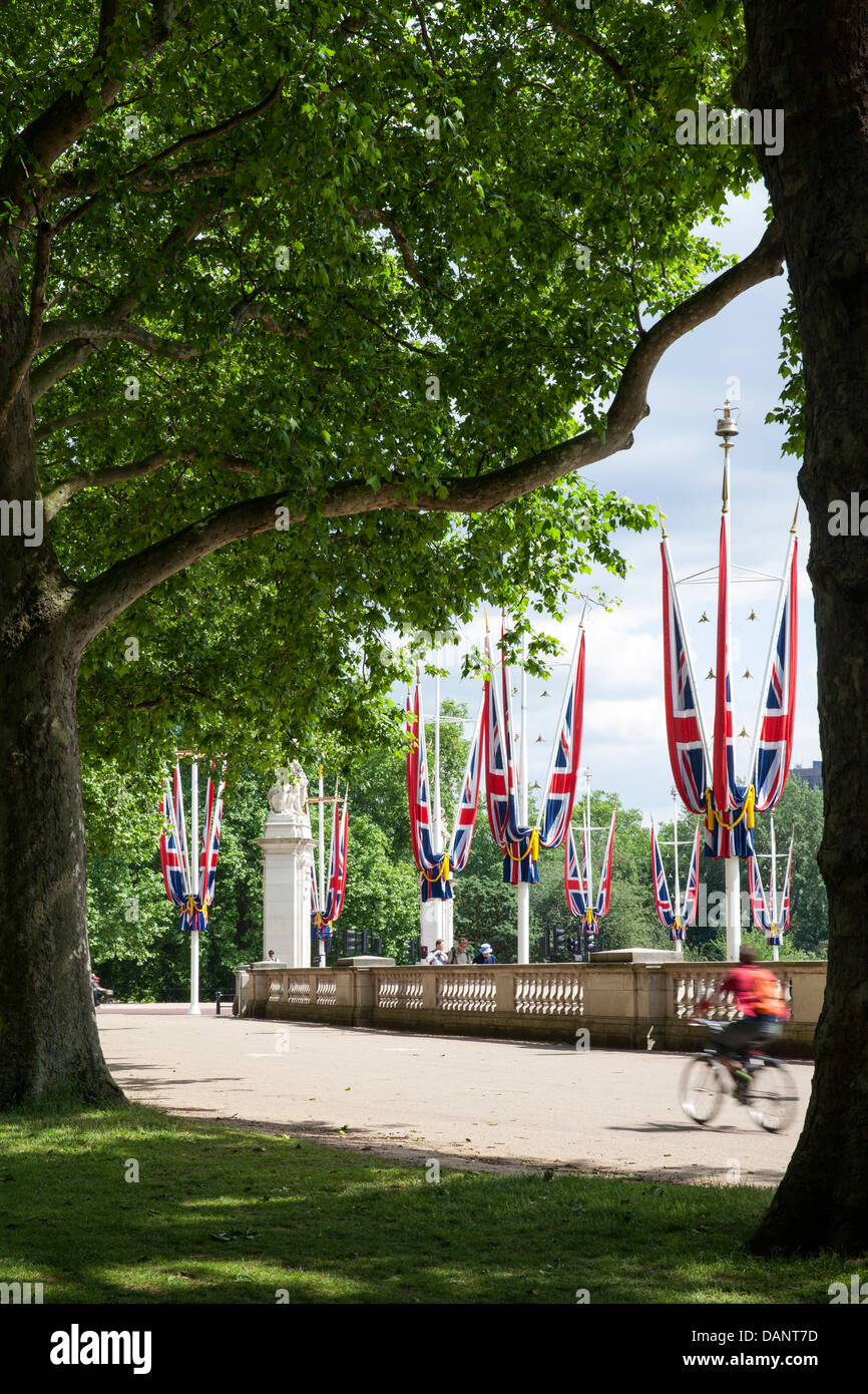 The Green Park, London, United Kingdom. Architect: John Nash, 1820. A cyclist rides past mature plane trees and Union Jack flags Stock Photo