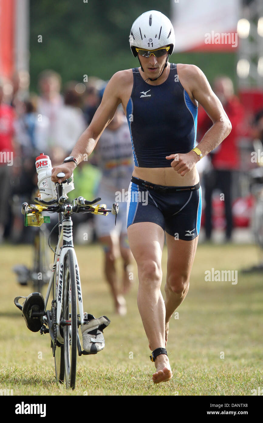 German triathlete Christian Ritter gets on his bike after the swimming etappe during the 10th Ironman Challenge in Roth, Germany, 10 July 2011. For the ironman, the participants have to swim 3,8 km, cycle 180 km and run 42,195 km. Photo: Daniel Karmann Stock Photo
