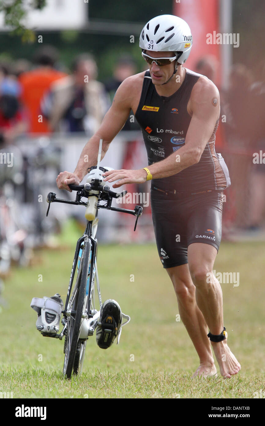 British triathlete Dion Harrison gets on his bike after the swimming etappe during the 10th Ironman Challenge in Roth, Germany, 10 July 2011. For the ironman, the participants have to swim 3,8 km, cycle 180 km and run 42,195 km. Photo: Daniel Karmann Stock Photo