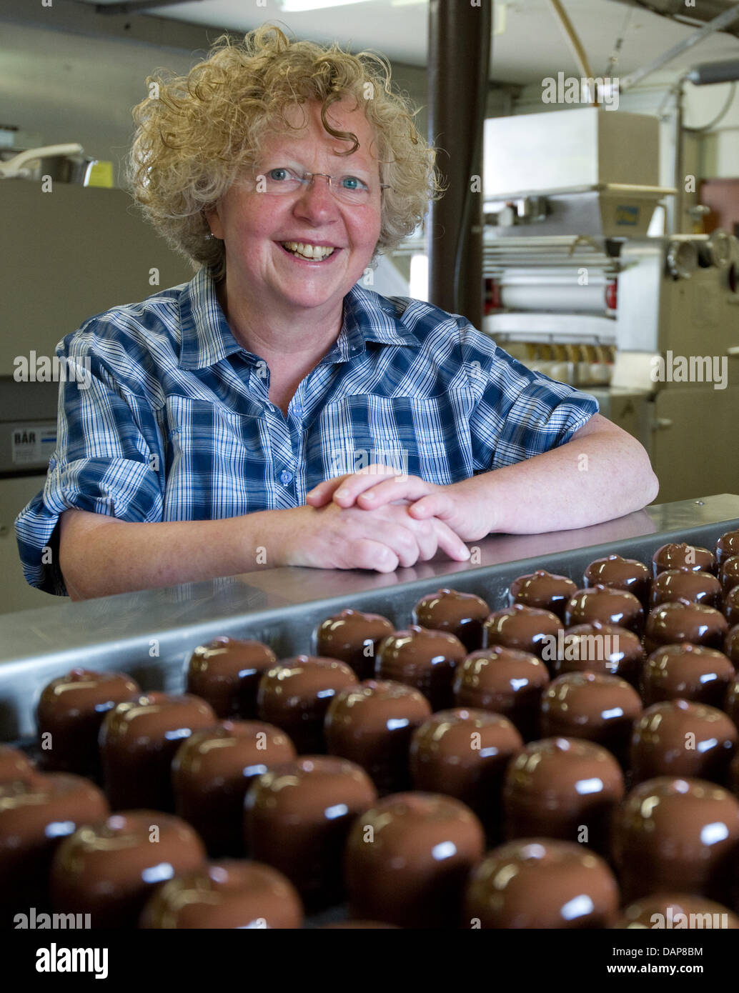 The owner of the sweets manufacturer 'Trauth', Marie-Luise Trauth, poses next to an assembly line of chocolate marshmallows at the factory in Herxheim near Landau, Germany, 07 July 2011. Photo: Uwe Anspach Stock Photo