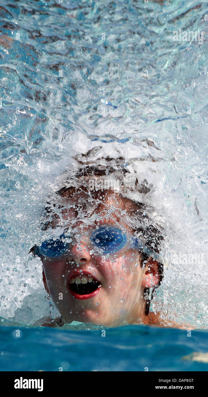 A young visitor to a swimming pool swims under and artificial waterfall