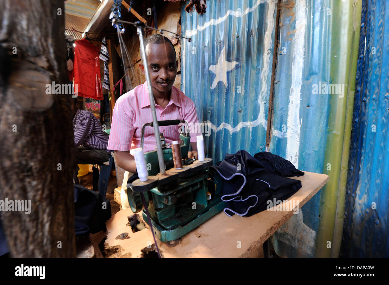 A man sews clothes on his sewing machine at a refugee camp in Dadaab, Kenya, 5 August 2011. They